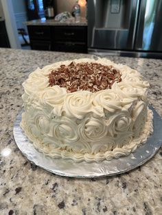 a cake sitting on top of a counter covered in frosting and pecanse