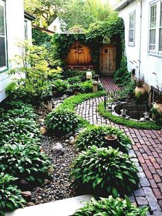 an outdoor garden with lots of plants and rocks in the center, surrounded by brick walkways