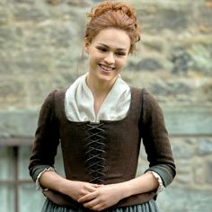 a woman with red hair wearing a brown and green dress