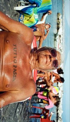 a man with no shirt standing in front of a group of people wearing bathing suits