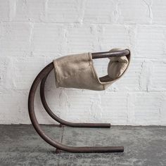 a chair that is sitting in front of a white brick wall with a wooden handle attached to it