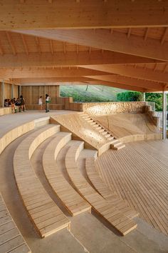 an empty wooden stage with steps leading up to the top and people sitting on benches in the background