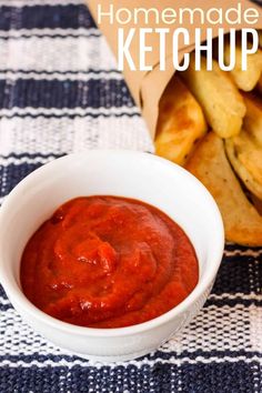 homemade ketchup in a white bowl next to french fries on a blue and white tablecloth