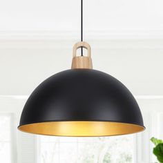 a black and gold pendant light hanging over a dining room table