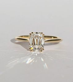 a yellow gold ring with an oval cut diamond in the center, on a white surface