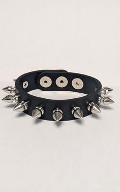 Single Row 1/2" Spiked wristband.       This is a finely made Vegan Friendly wristband. It is made out of a heavy duty Vegan Friendly Material.  available in Black.   This is a one-size fits all band. It will fit most wrists ( 5" up to 8" ). 3/4" wide band with snaps for adjustable fastening/closure.    The 1/2" Tall Spikes are a screwback design. These spikes are Solid Brass with a nice nickel plating ( making them look like Chrome/Silver ). Spiked Wristband, All Band, Nickel Plating, Chrome Silver, Punk Bands, Leather Gifts, Wide Bands, Punk Rock, Vegan Friendly