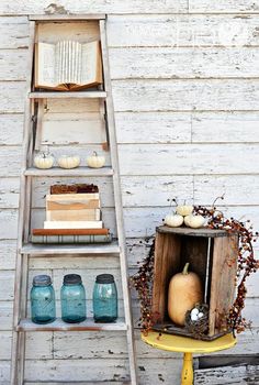 an old ladder leaning against a white wall with books and vases on the shelf