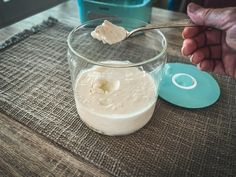 a person is spooning cream into a glass bowl