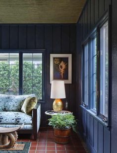 a living room filled with furniture next to a window and potted plants on the floor