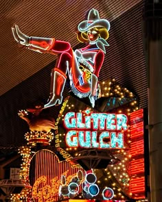 a neon sign that says glitter gulch on the side of a building with lights around it