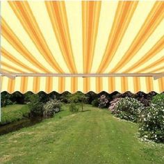 a yellow and white striped awning over a lush green field