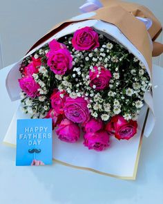 a bouquet of pink roses and baby's breath sits next to a father's day card