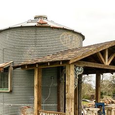 an old metal silo sitting on top of a wooden deck next to a building