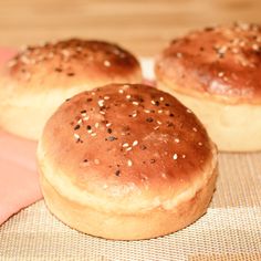 three sesame seed rolls sitting on top of a piece of cloth next to each other