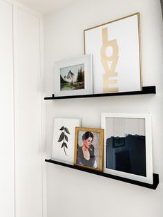 three black shelves with pictures and framed photos on them in a white walled wall area