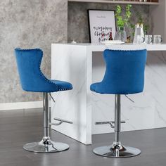 two blue barstools sitting next to each other in front of a white counter