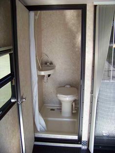 a small bathroom with a toilet and shower in it's stall, next to a sliding glass door