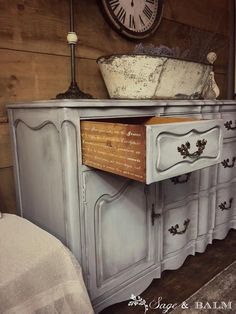 an old dresser with a clock on the wall behind it