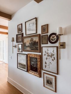 there are many framed pictures on the wall in this room with wood flooring and white walls