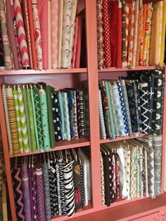 a pink bookcase filled with lots of different colored fabrics