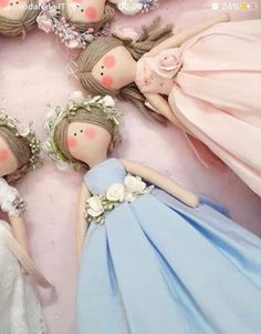 four dolls are laying on the floor with flowers in their hair, and one is wearing a blue dress