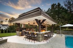 an outdoor kitchen and dining area next to a swimming pool