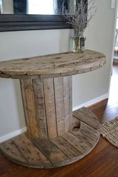 a round wooden table sitting on top of a hard wood floor next to a mirror