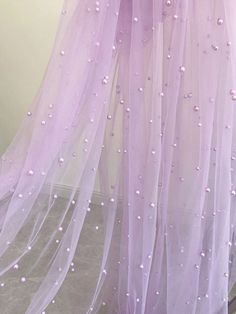 there is a purple dress with white pearls on the bottom and pink tulle skirt