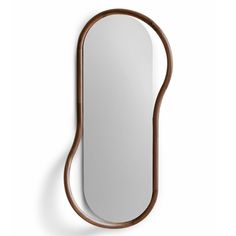 an oval mirror hanging on the wall next to a wooden frame and brown leather strap