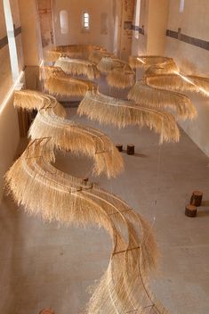 several straw umbrellas are lined up on the floor in a room with no people