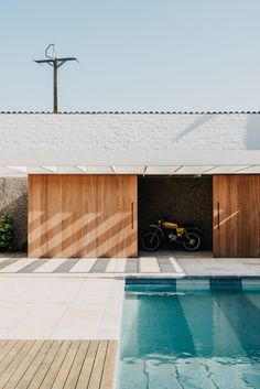 an outdoor swimming pool with a bike parked in the doorway and wooden slats on the wall