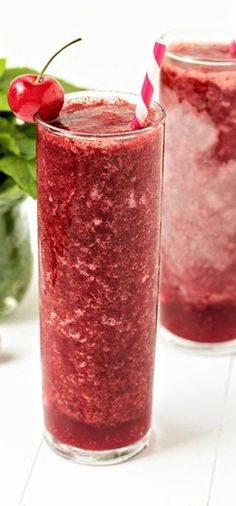 two glasses filled with smoothie and garnished with cherries