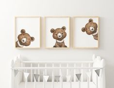 three framed teddy bears are hanging on the wall above a crib in a white nursery