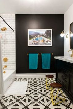 a black and white bathroom with gold accents on the shower, rugs and towels