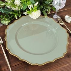 an empty plate on a wooden table with flowers and silverware in the foreground