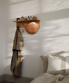 a bedroom with a bed, coat rack and pillows on the wall next to it