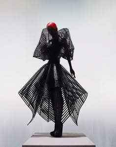 a woman with an apple on her head is standing in front of a sculpture that appears to be made out of wire