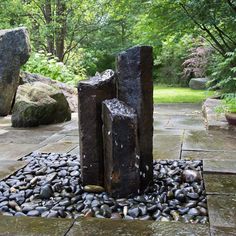 a rock garden with rocks and stones on the ground, in front of some trees