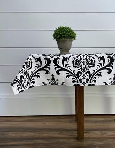 a potted plant sitting on top of a table covered in a black and white damask