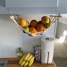 a basket filled with lots of fruit sitting on top of a wooden table next to a toilet paper roll