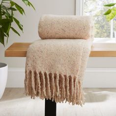 a blanket on a table next to a potted plant in front of a window