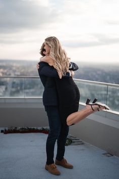 a pregnant woman hugging her husband on top of a building