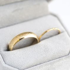 two gold wedding rings sitting in a box