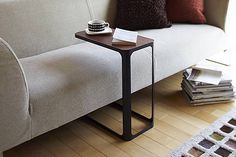 a white couch sitting next to a wooden table on top of a hard wood floor