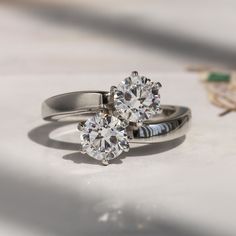 two engagement rings sitting on top of each other next to a flower shaped diamond ring