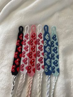 four different colored knitted hair ties with hearts on them sitting on a white sheet