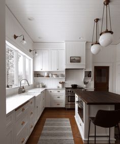 a black and white photo of a kitchen with wood flooring, cabinets, counter tops, and an island