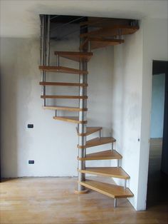 a spiral staircase in an empty room with wood floors