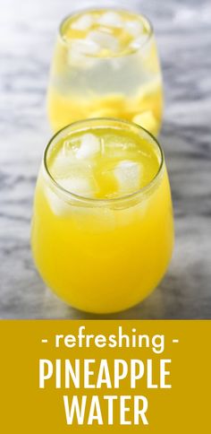 two glasses filled with pineapple water on top of a table