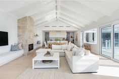 a living room filled with white furniture and a flat screen tv mounted on the wall